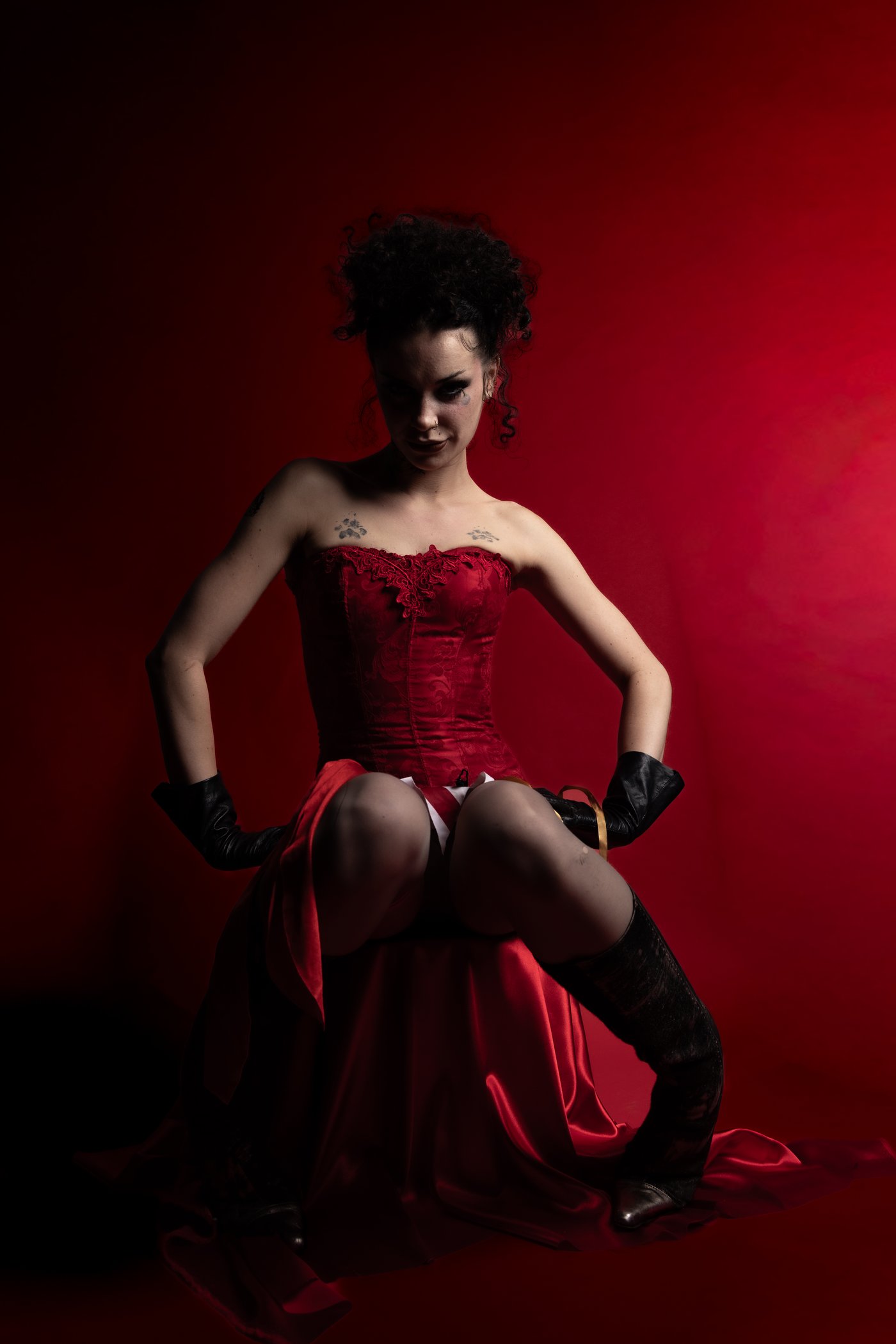 Red corset, hands on hips, dark dramatic lighting