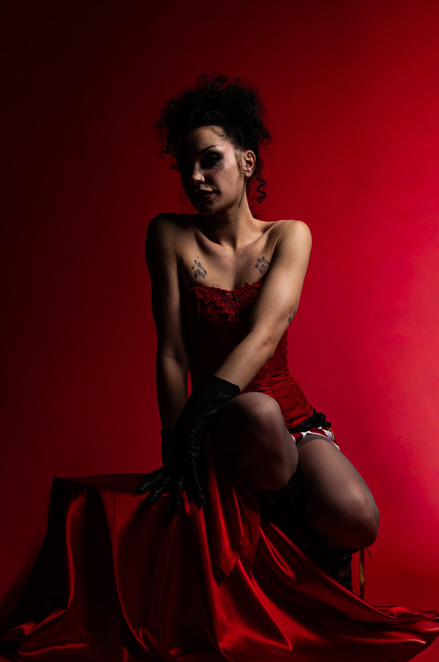 Seated figure in red corset with knee-high boots