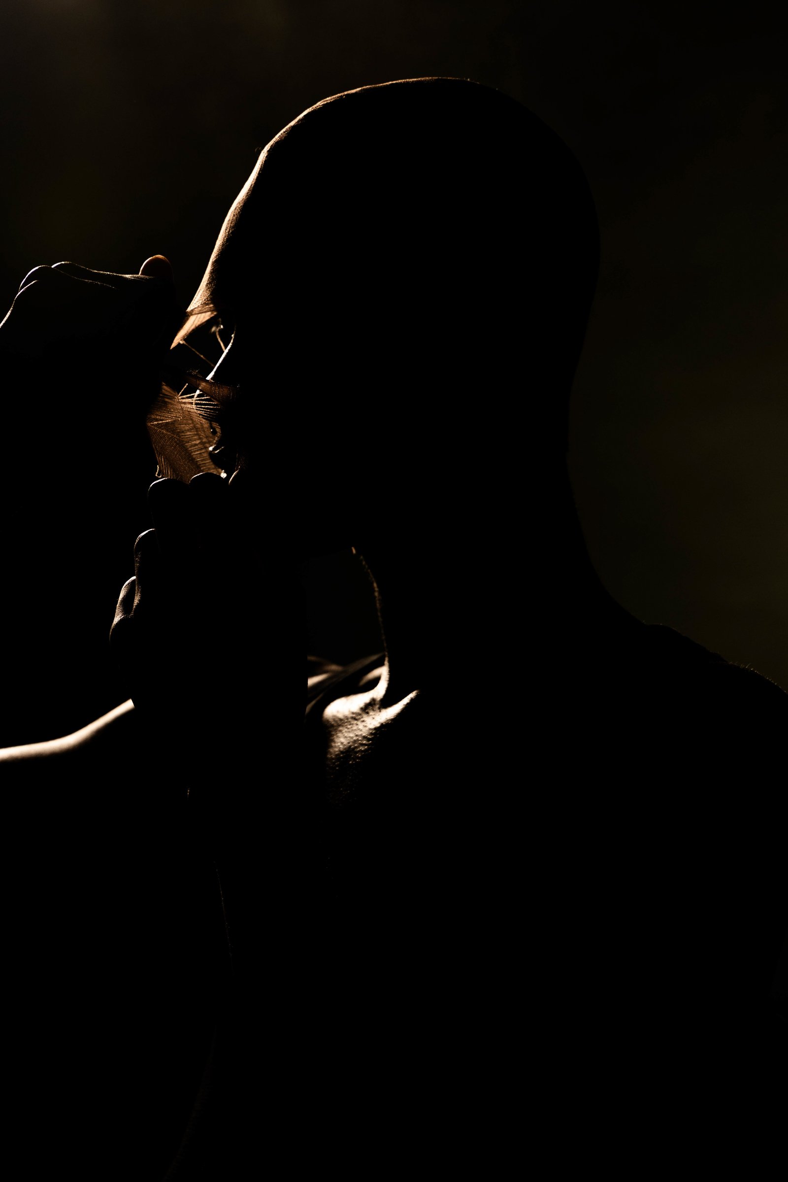 Silhouette with hand pulling fabric from the face